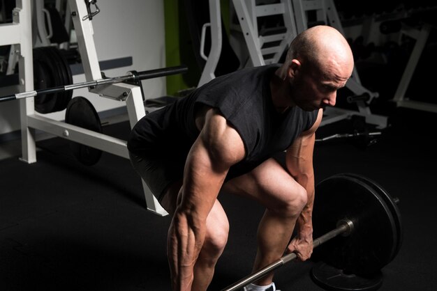 Bodybuilder faisant des exercices de poids lourds pour le dos avec des haltères dans une salle de sport moderne