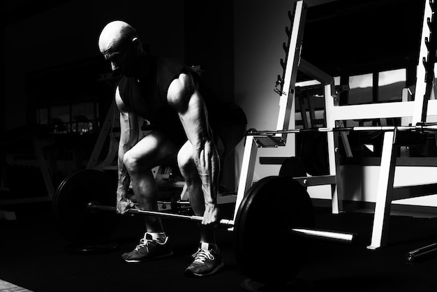 Bodybuilder faisant des exercices de poids lourds pour le dos avec des haltères dans une salle de sport moderne