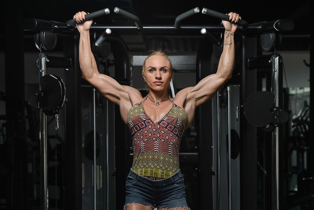 Bodybuilder féminin faisant des exercices de poids lourds pour le dos dans la salle de gym