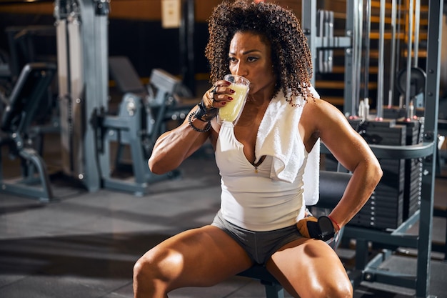 Bodybuilder féminin prenant une gorgée d'une boisson protéinée