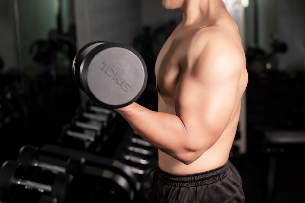 Bodybuilder homme fitness musculaire est séance d'entraînement avec des haltères dans la salle de gym