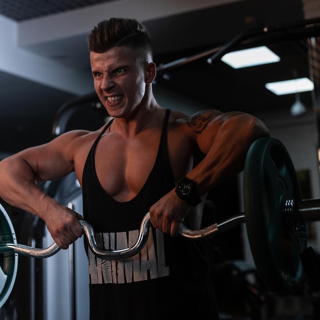 Bodybuilder homme fort émotionnel s'entraînant et faisant des exercices dans la salle de gym