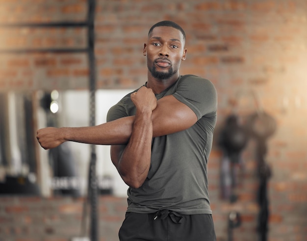 Bodybuilder homme noir et étirement dans la salle de gym pour la santé de remise en forme ou l'exercice avec les bras musculaires ou la concentration Homme fort ou échauffement pour l'entraînement ou la performance pour un bien-être ou une vie saine