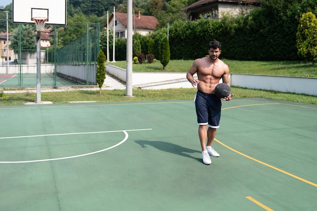 Bodybuilder jouant au basket en plein air