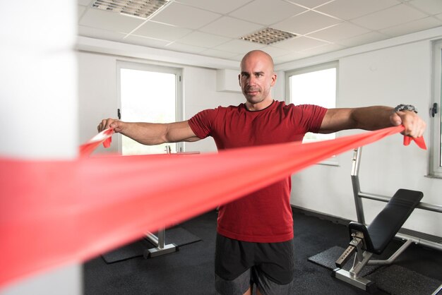 Bodybuilder masculin exerçant dans une salle de sport avec bande de résistance