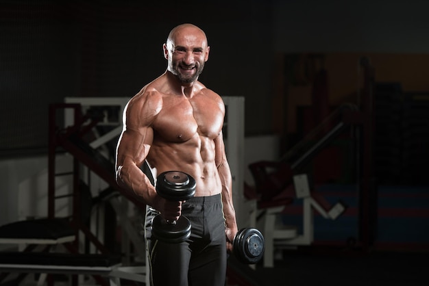 Bodybuilder mature exerçant des biceps avec haltère