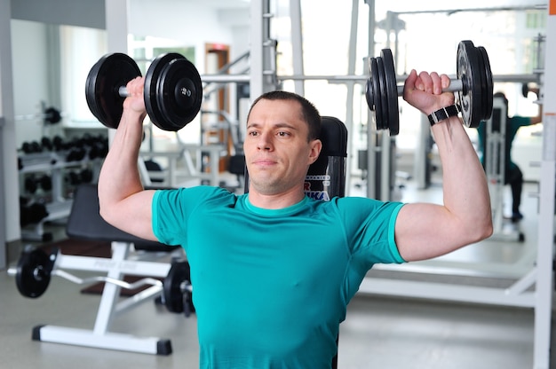 Photo bodybuilder musclé déchiré avec des haltères