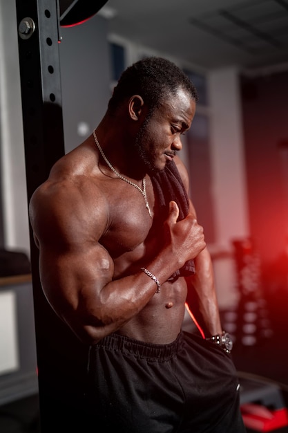 Bodybuilder musclé posant pour la caméra seins nus. Homme noir torse nu dans une salle de sport.