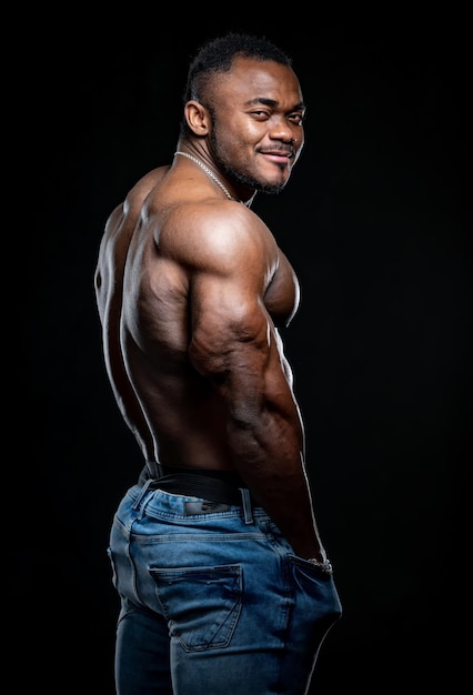 Bodybuilder musclé sexy montrant son torse nu. Guy de remise en forme athlétique en jeans posant pour la caméra.