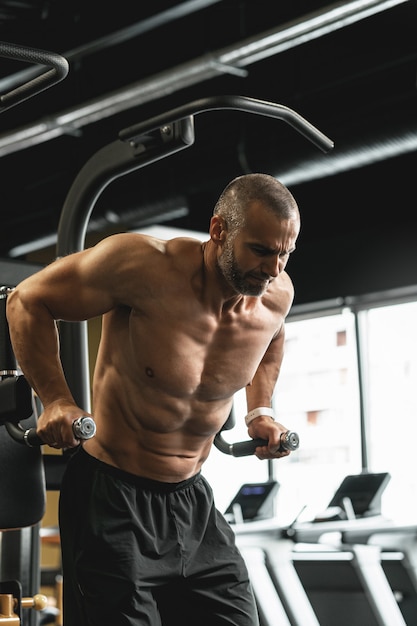 Bodybuilder musculaire faisant des trempettes pour les triceps et les muscles de la poitrine pendant son entraînement dans la salle de gym