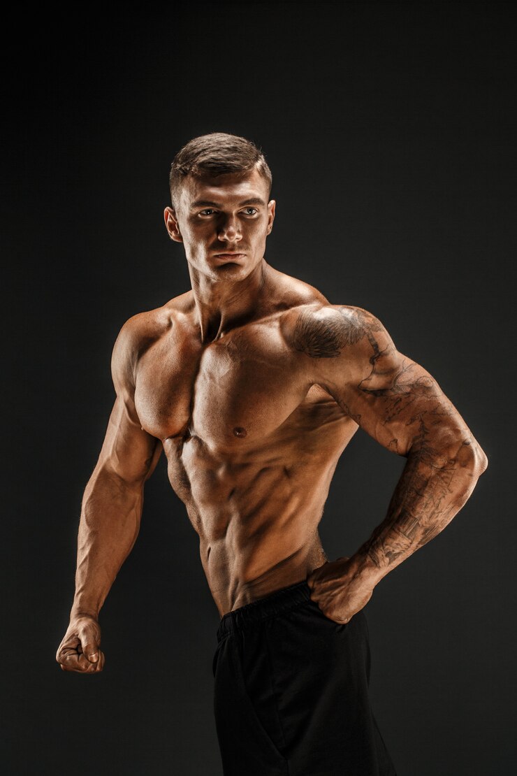 Photo bodybuilder posant fitness homme musclé sur scène sombre