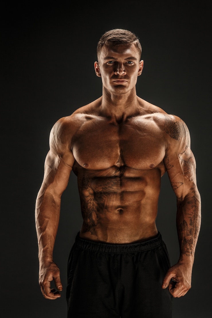 Photo bodybuilder posant fitness homme musclé sur scène sombre