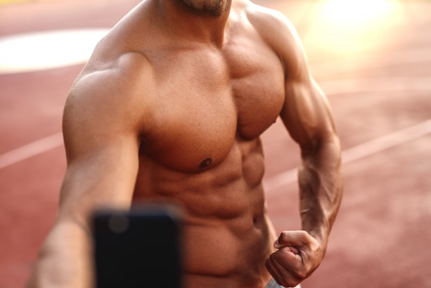 Bodybuilder prenant selfie à l'extérieur.