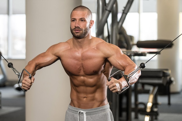 Bodybuilder travaille sur sa poitrine avec un câble croisé dans une salle de sport