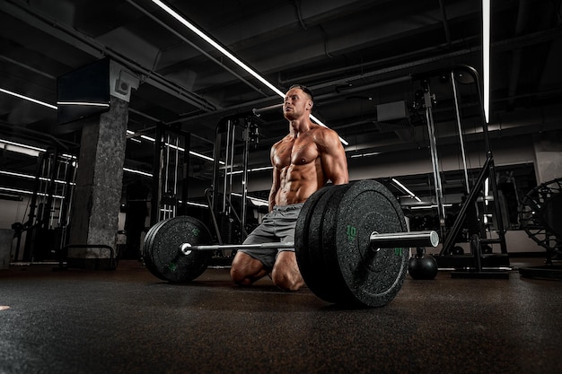 Un bodybuilder va soulever un travail d'haltère dans une salle de sport avec de gros poids avec un équipement de sport un haltère lourd