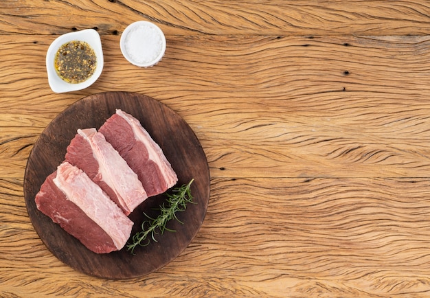 Bœuf ancho cru tranché, coupe typiquement argentine, sur planche de bois avec assaisonnements et espace de copie.