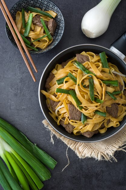 Boeuf chinois chow mein dans une poêle sur fond noir