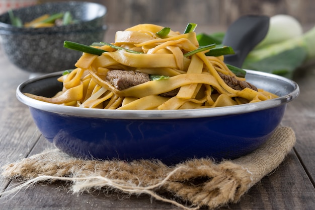 Boeuf chinois chow mein dans une poêle sur une table en bois