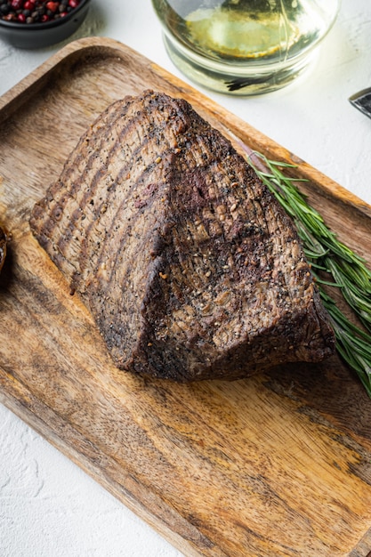 Bœuf coupé au four, sur plateau en bois, sur table blanche