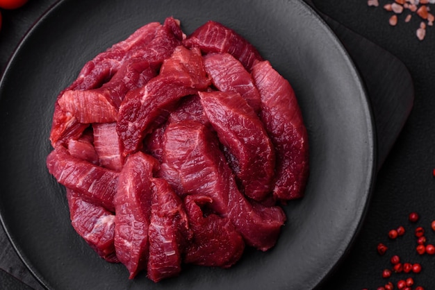 Boeuf cru juteux avec du sel d'épices et des herbes sur un fond de béton foncé