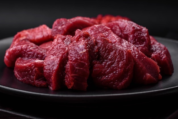 Boeuf cru juteux avec du sel d'épices et des herbes sur un fond de béton foncé