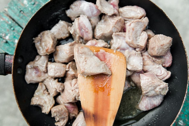 Boeuf frit dans une poêle. processus de cuisson du rosbif. vue de dessus. plats ruraux simples. vue rapprochée