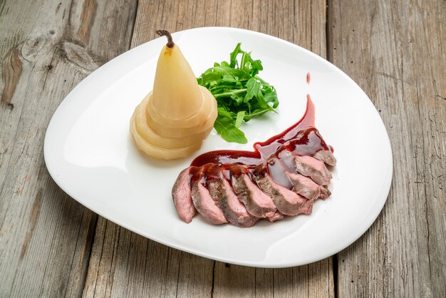 Boeuf grillé mi-saignant à la poire, légumes grillés, sur une surface en bois