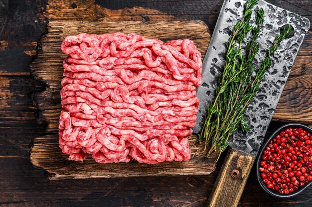 Bœuf haché cru, viande hachée aux herbes et épices sur une planche à découper en bois