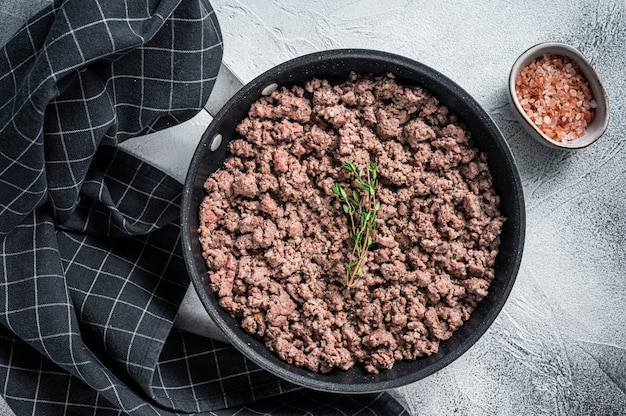 Bœuf haché frit et viande d'agneau dans une poêle avec des herbes.