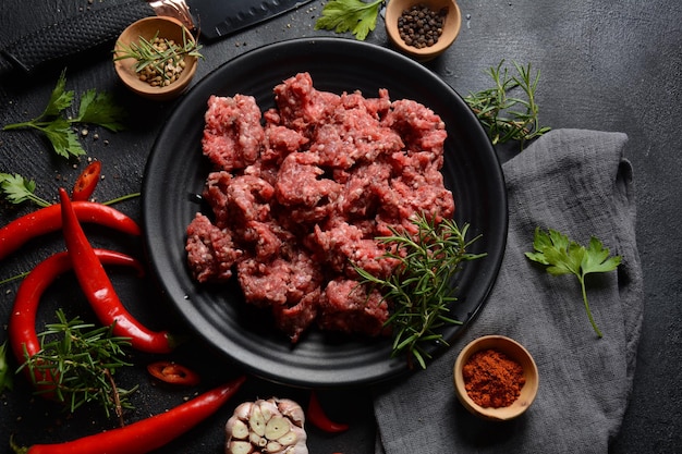 Boeuf haché. Viande hachée avec des ingrédients pour la cuisson sur fond noir