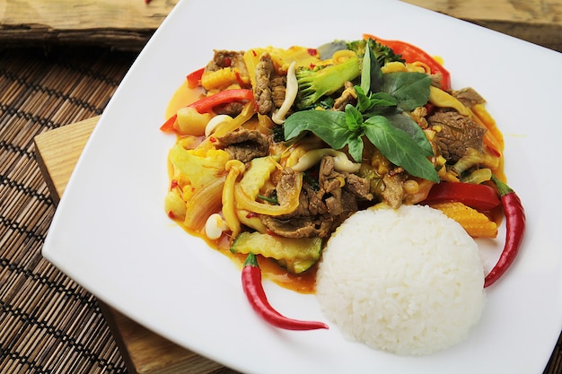 Bœuf oriental avec des légumes et du riz sur une assiette blanche avec des baguettes chinoises