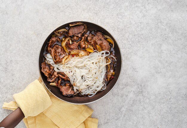 Boeuf en sauce avec oignons et pâtes dans une poêle. Cuisine asiatique. Vue d'en-haut.