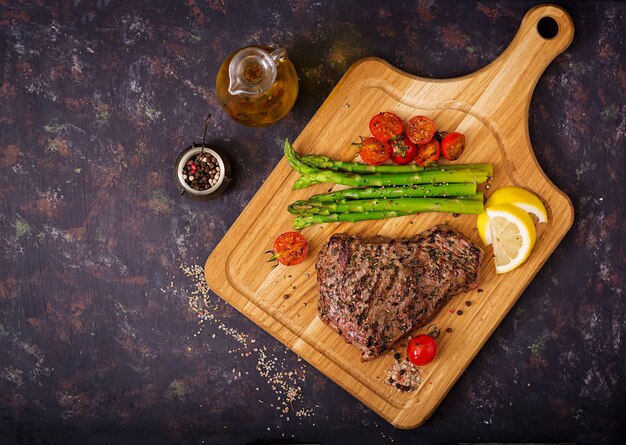 Bœuf sauté juteux aux épices sur une planche de bois et garniture d&#39;asperges.