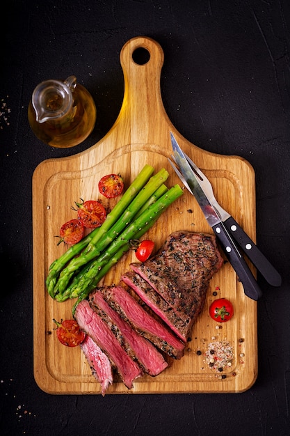 Bœuf sauté juteux aux épices sur une planche de bois et garniture d&#39;asperges.