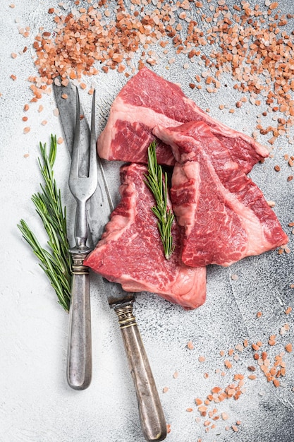 Bœuf de surlonge de Silverside coupé de la viande crue sur une table de boucher avec des herbes Fond blanc Vue de dessus