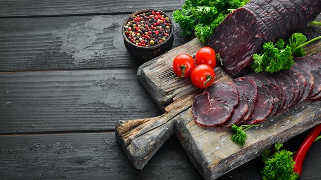 Boeuf de veau séché aux épices et herbes. Boeuf séché sur une vieille table noire. Vue de dessus. Espace libre pour votre texte.