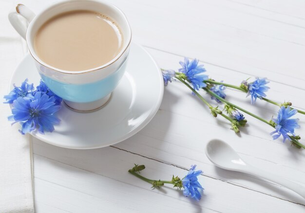 Boire de la chicorée dans une tasse sur la table en bois blanc