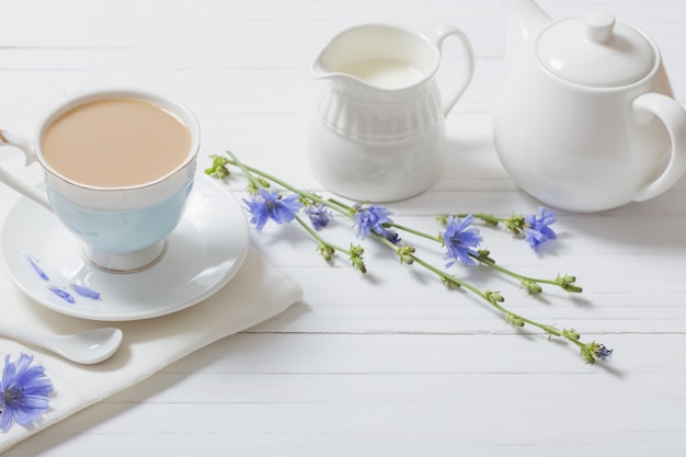 Boire de la chicorée dans une tasse sur la table en bois blanc