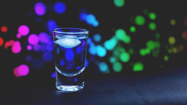 Boire du verre avec de la glace au bar sur fond abstrait de couleur néon