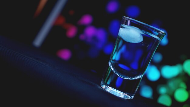 Boire du verre avec de la glace au bar sur fond abstrait de couleur néon