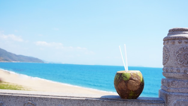 Boire de l'eau de coco sur une plage tropicale. Plage de la mer en arrière-plan