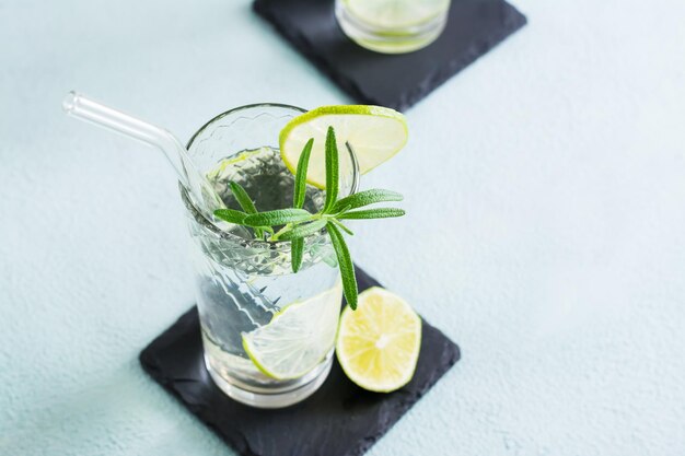 Boire de l'eau rafraîchissante avec de la chaux et du romarin dans des verres avec de la paille écologique Closeup Copy space