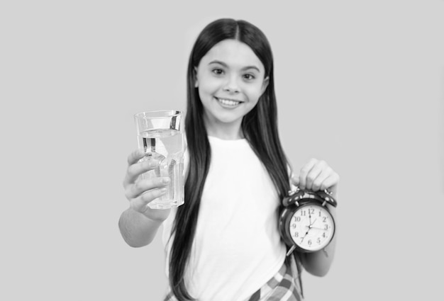 Boire le matin par jour être hydraté enfant tenir le verre et l'horloge enfant avoir soif adolescente réveil sain enfance temps de boire de l'eau équilibre hydrique dans l'hydratation corporelle vitalité