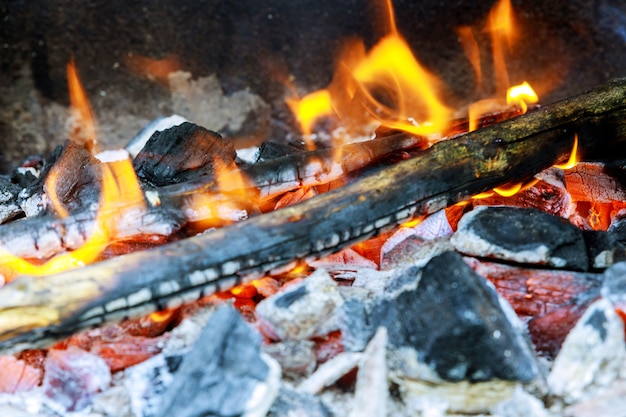 Photo bois de chauffage brûlant dans un brasier sur une flamme jaune vif d'un arbre, charbons gris foncé à l'intérieur d'un brasier en métal.