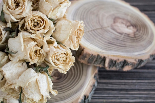 Photo le bois coupé avec des roses séchées; des roses sèches sur un arbre coupé. décoration vintage