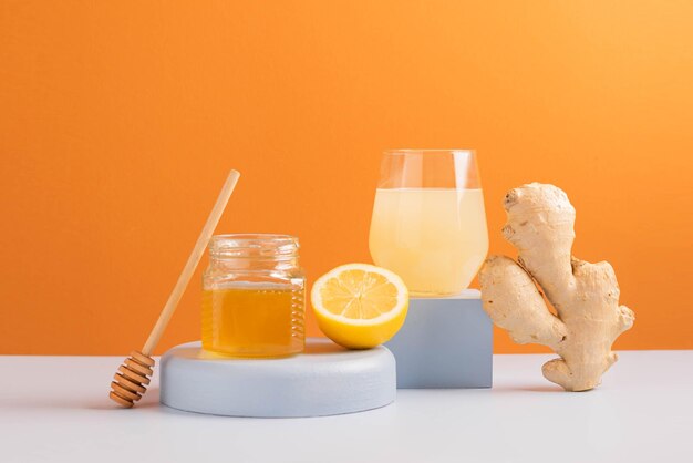 Boisson antioxydante miel de citron gingembre frais dans un verre minimalisme de podium de fond coloré à la mode