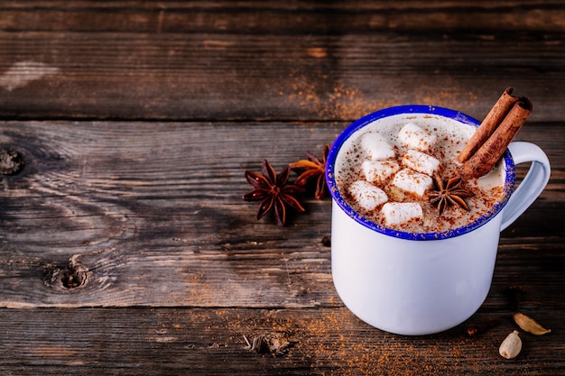 Boisson au cacao chaud avec de la cannelle et des guimauves sur fond de bois