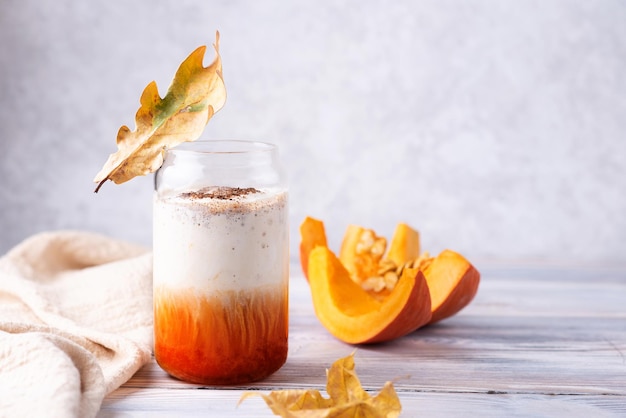 Boisson au café d'automne avec crème fouettée, latte épicé à la citrouille en verre sur une table en bois blanc, espace pour copie.