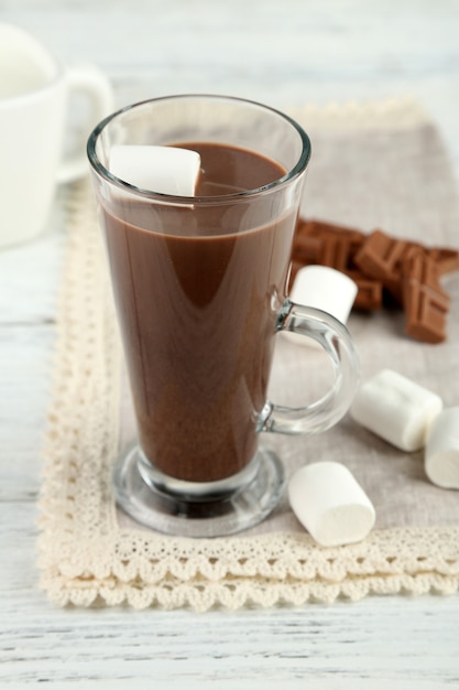 Boisson au chocolat avec des guimauves dans une tasse, sur fond de bois