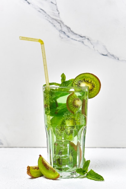 Boisson au citron vert kiwi avec menthe et glace en verre gros plan sur une surface claire